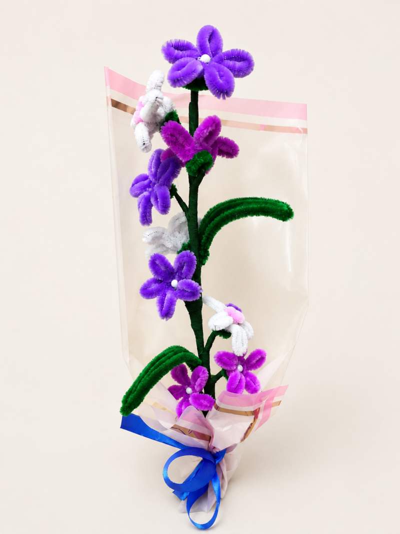 Handmade purple and white pipe cleaner flower bouquet wrapped with decorative paper and blue ribbon